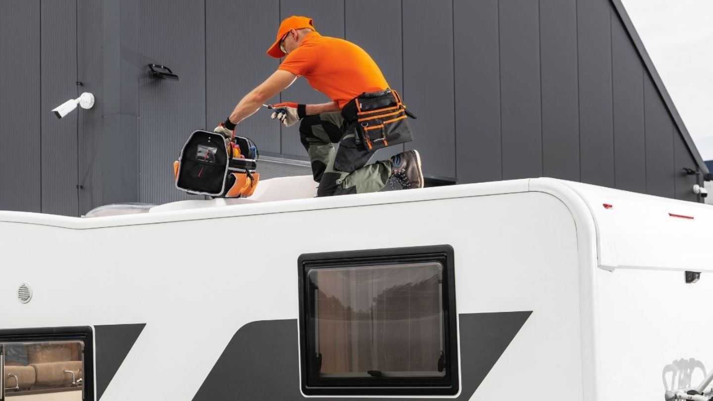 RV technician sealing a roof under a clear Florida sky at a campground near Orlando